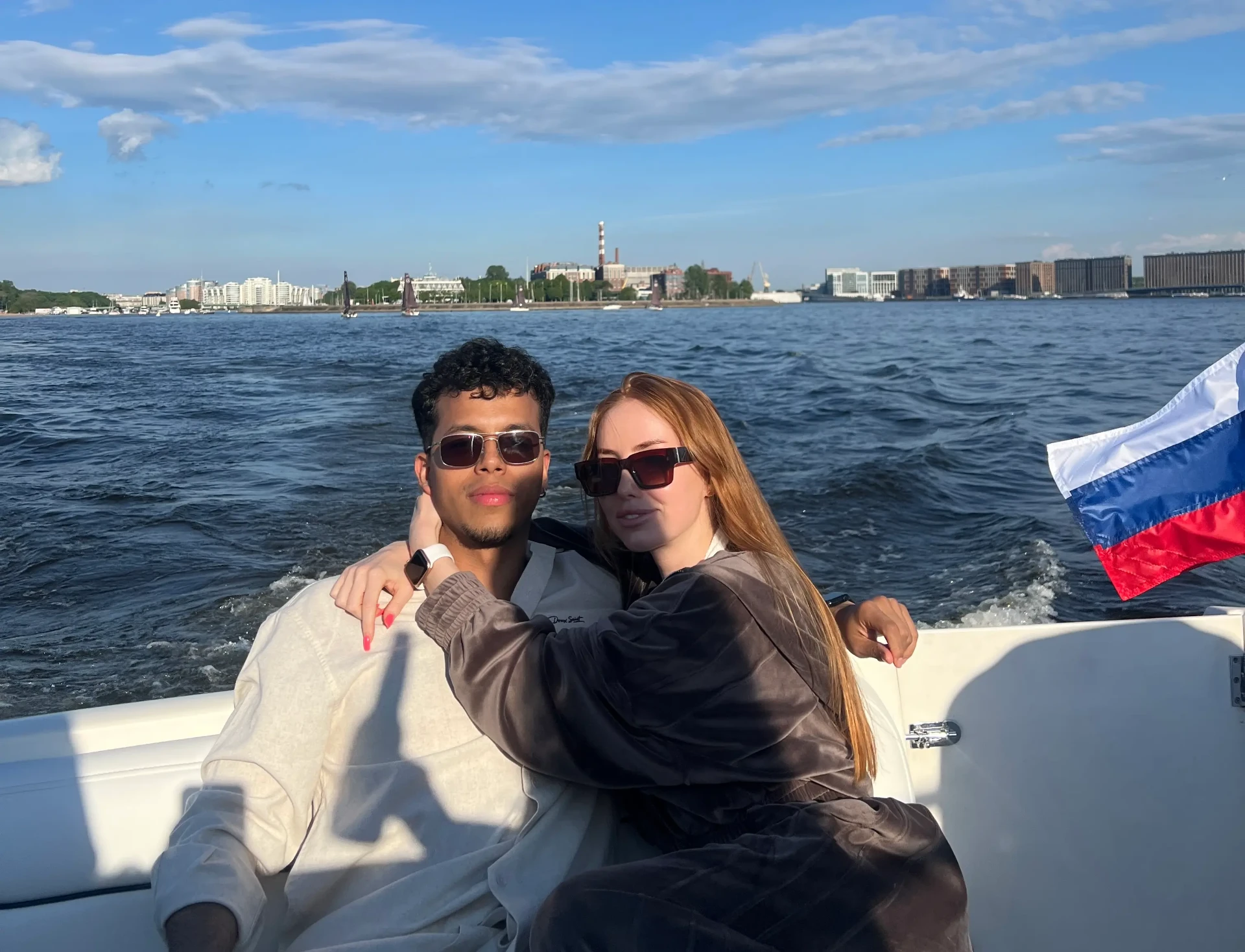 Mariano con su pareja en un barco en Moscú, con la bandera rusa al fondo